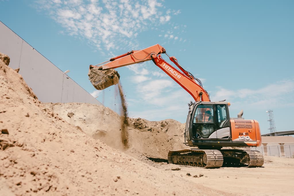 Dirt streaming out of an excavator bucket onto the pile