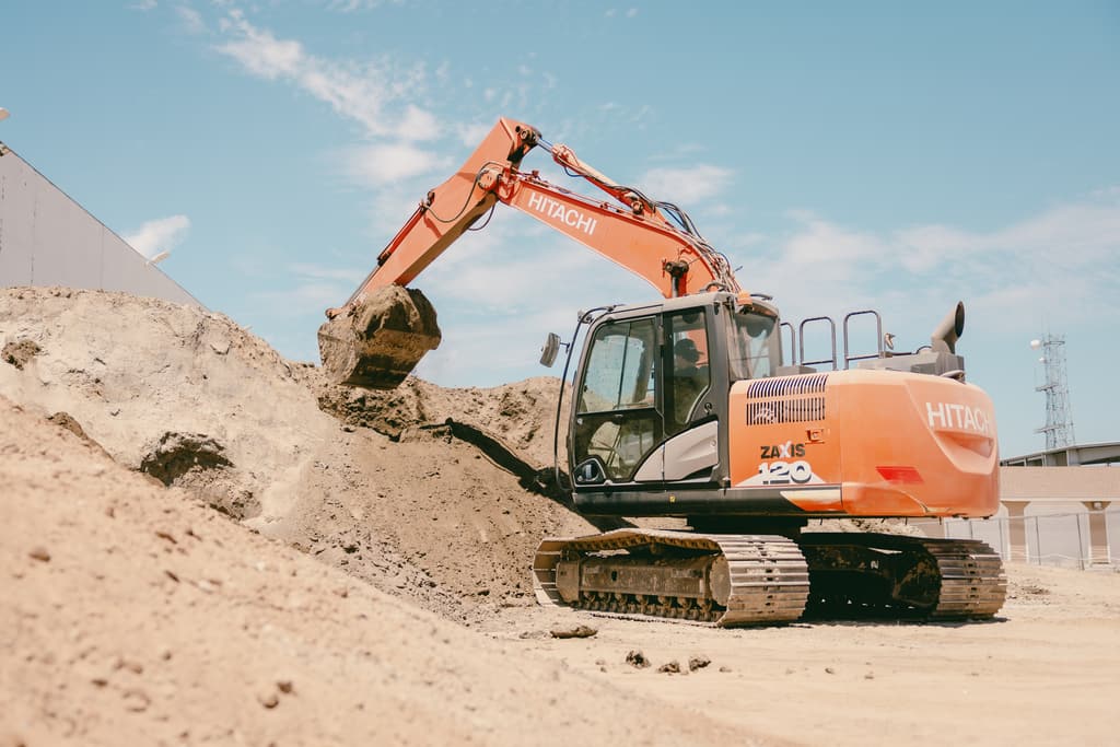 Excavator with a full bucket at the base of the stockpile