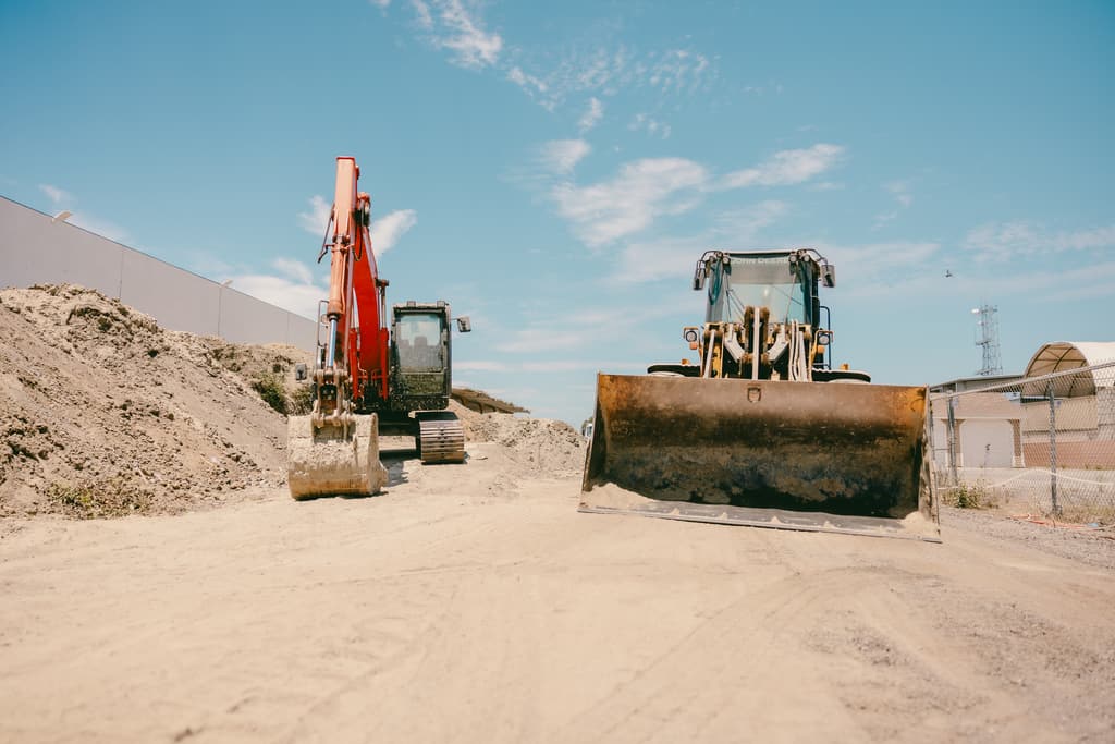 Excavator and wheel loader working at the base of the stockpiles